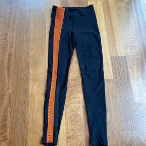 Koral black legging with orange mesh down the right leg.